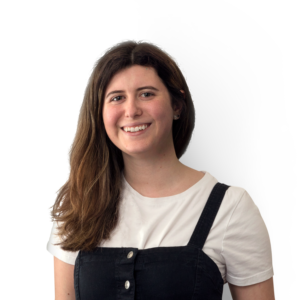 Young lady with long black hair over her right shoulder fashioning a black dungaree style ad white t-shirt