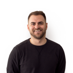 A man with short mousy brown hair a well groomed beard and wearing a black jumper